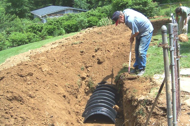 Installer checking the level of a chamber trench on a hillside